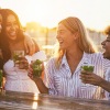 a group of women laugh together with drinks in hand